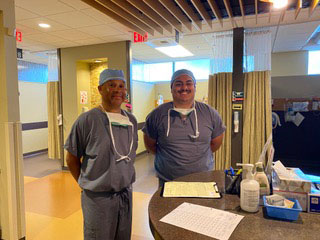 2 medical professionals in scrubs standing in a hospital lobby