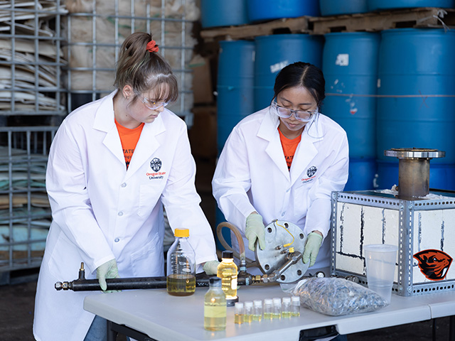 two researcher in lab coat examine experiment equipment with glowing vials of liquid