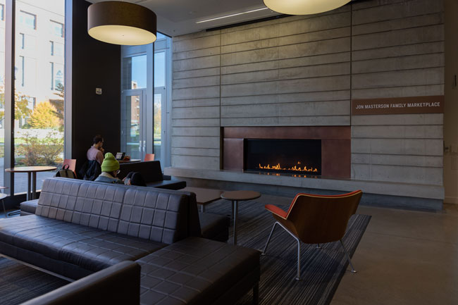 couch and tables in front of lit fireplace surrounded by stone slab