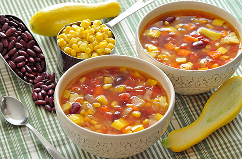 2 bowls of soup next to 2 scoops of beans