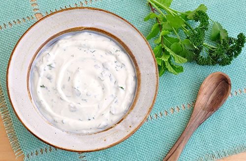 bowl of yogurt with herbs scattered throughout